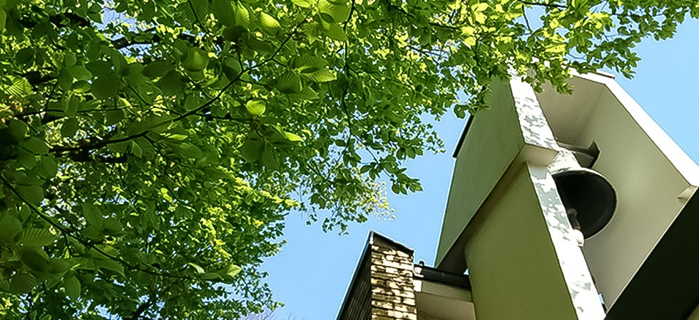 Glockenturm in der Sonne mit Baumkrone